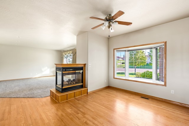 unfurnished living room with baseboards, visible vents, wood finished floors, and a multi sided fireplace