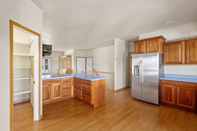 kitchen featuring light countertops, stainless steel refrigerator with ice dispenser, light wood finished floors, and a peninsula