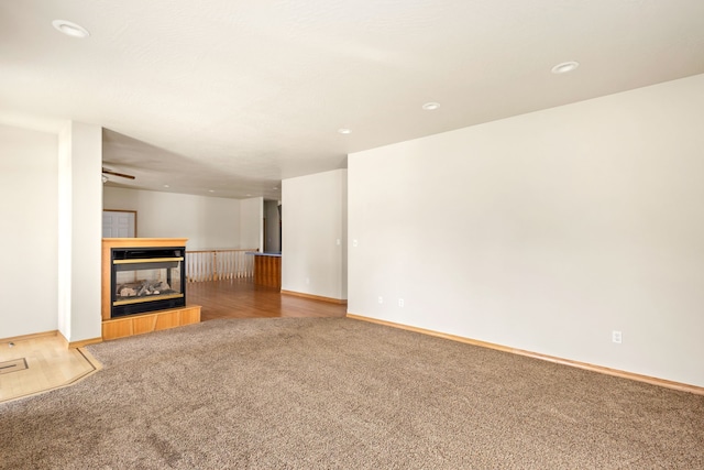 unfurnished living room with recessed lighting, baseboards, carpet flooring, and a tiled fireplace