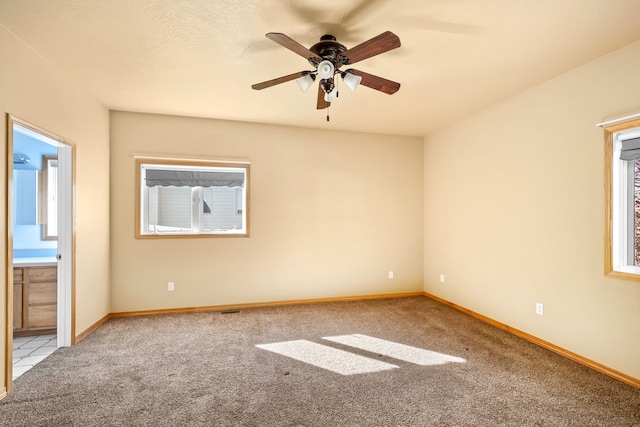 carpeted spare room with ceiling fan, baseboards, and a textured ceiling