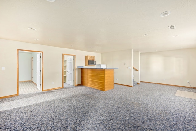 unfurnished living room featuring visible vents, stairs, baseboards, and light colored carpet