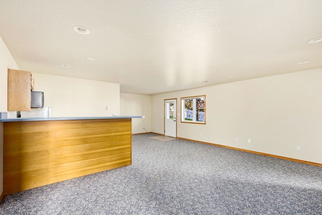 interior space featuring light carpet, a textured ceiling, and baseboards