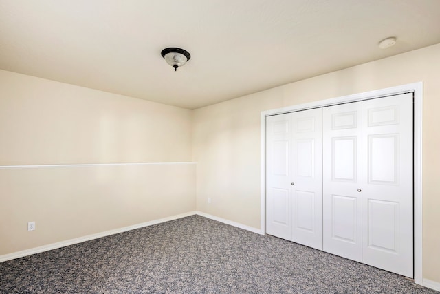 unfurnished bedroom with carpet floors, baseboards, and a closet