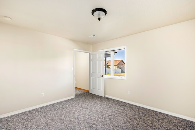 carpeted empty room featuring baseboards