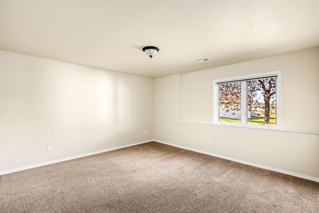 carpeted empty room with baseboards, visible vents, and a textured ceiling