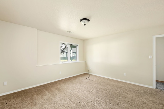 spare room featuring carpet flooring, visible vents, baseboards, and a textured ceiling