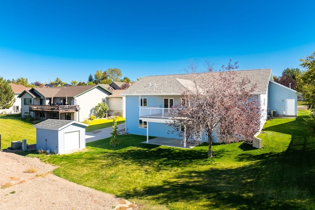 view of front of property featuring a balcony, an outdoor structure, a lawn, a residential view, and a storage unit