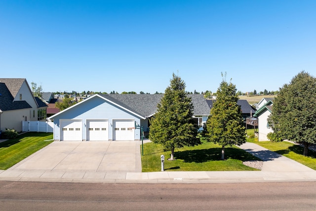 view of front of home featuring an attached garage, fence, driveway, a residential view, and a front lawn