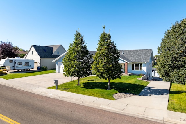 view of front of house with an attached garage, concrete driveway, a shingled roof, and a front yard