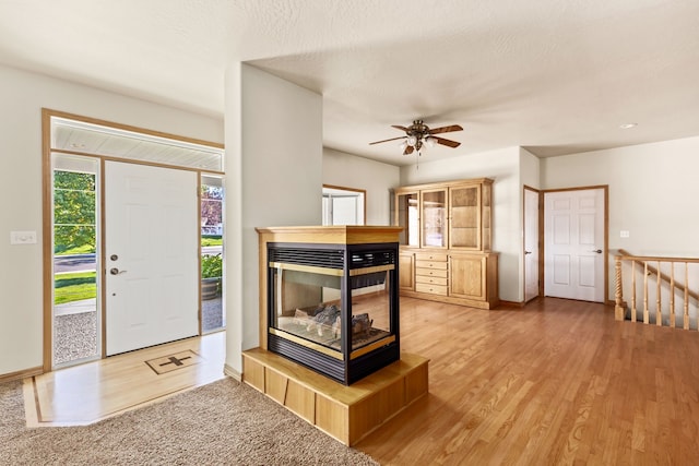 foyer featuring a textured ceiling, a fireplace, light wood-style flooring, and baseboards