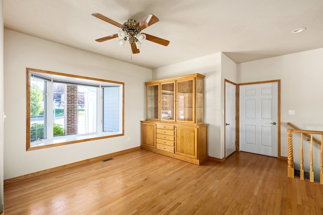 unfurnished bedroom featuring light wood-type flooring, visible vents, ceiling fan, and baseboards