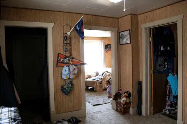 hallway with carpet and wood walls