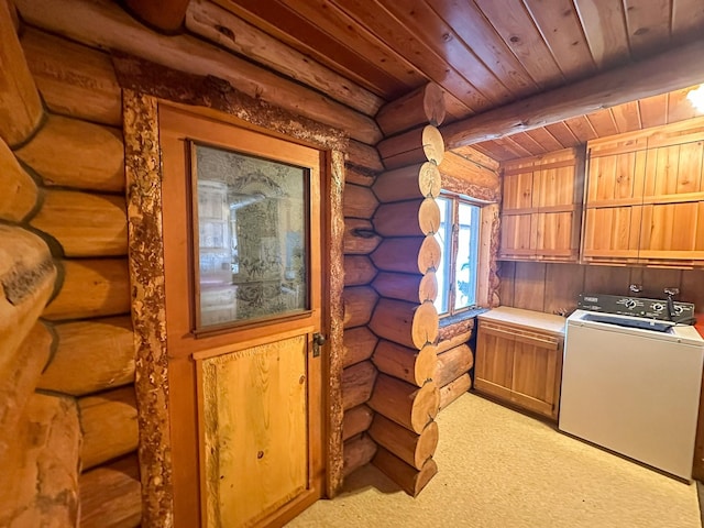 clothes washing area featuring cabinets, washer / clothes dryer, rustic walls, and wooden ceiling