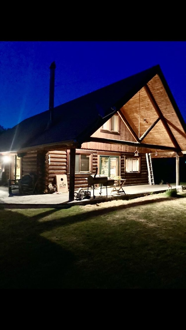 back house at night featuring a patio and a lawn