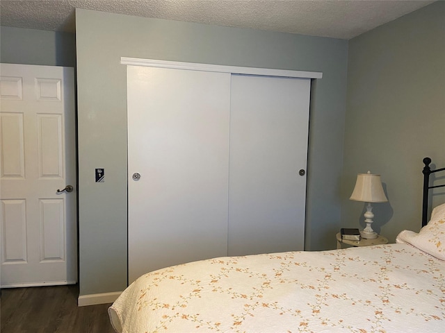 bedroom featuring dark hardwood / wood-style floors, a textured ceiling, and a closet