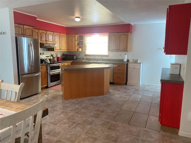 kitchen with sink, light tile patterned floors, appliances with stainless steel finishes, a textured ceiling, and a kitchen island