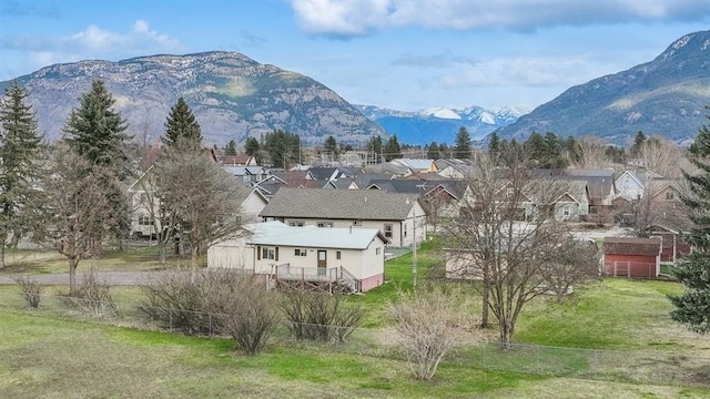 185 Veteran Dr, Columbia Falls, MT 59912 - yard covered in snow with a storage shed, an outbuilding, a mountain view, and fence
