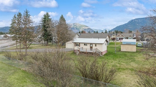 185 Veteran Dr, Columbia Falls, MT 59912 - back of house featuring a yard, a deck with mountain view, fence, and an outbuilding