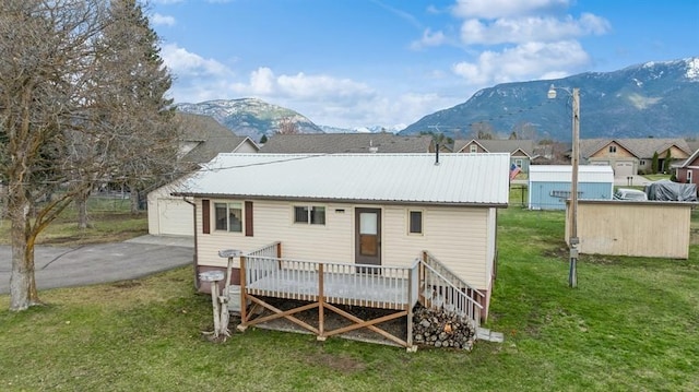 185 Veteran Dr, Columbia Falls, MT 59912 - rear view of property featuring a yard, metal roof, a garage, aphalt driveway, and a deck with mountain view
