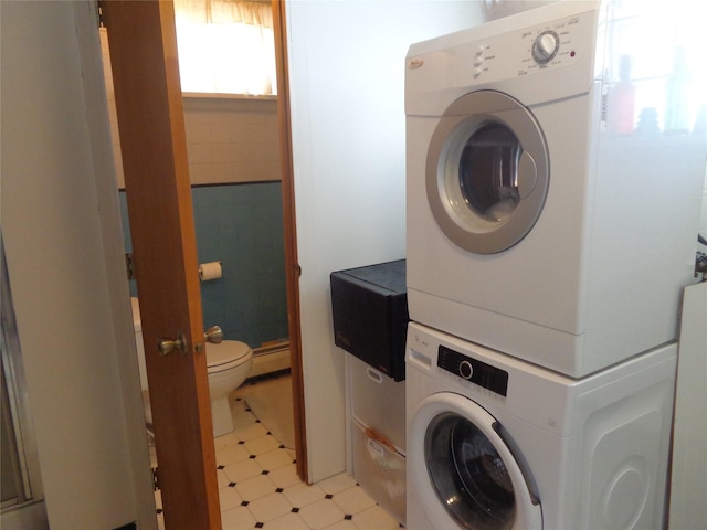 laundry room featuring stacked washer and dryer and a baseboard radiator