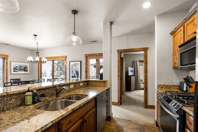 kitchen with sink, hanging light fixtures, light stone counters, stainless steel appliances, and an inviting chandelier