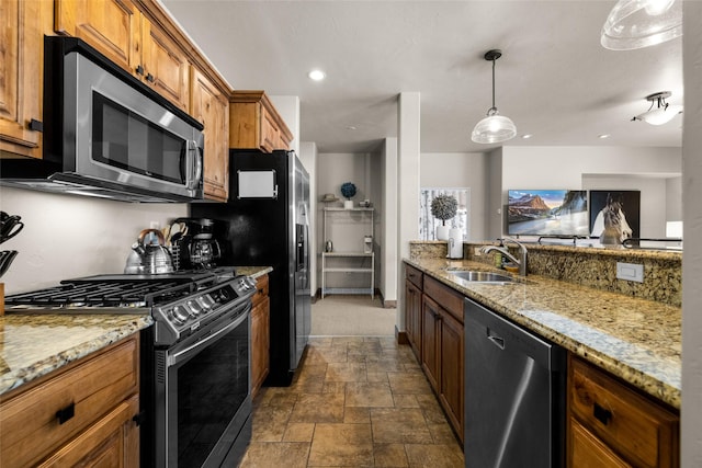 kitchen with appliances with stainless steel finishes, light stone countertops, sink, and hanging light fixtures