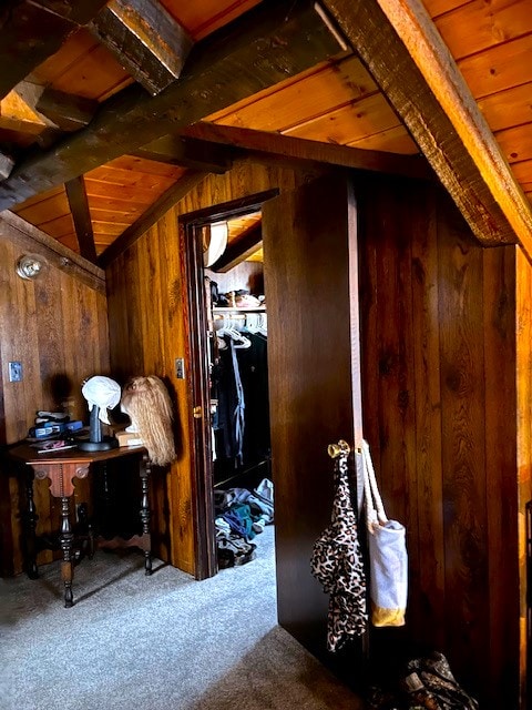 interior space with carpet floors, vaulted ceiling with beams, wood ceiling, and wooden walls