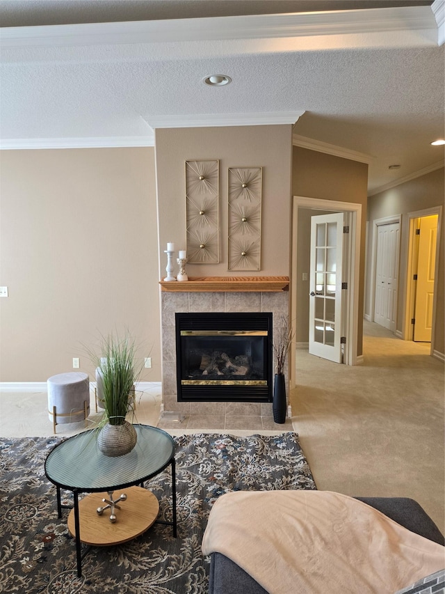 living room with ornamental molding, a tiled fireplace, light carpet, and a textured ceiling