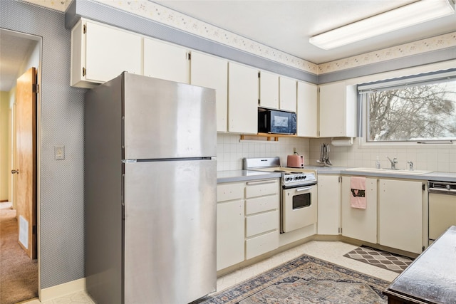 kitchen with light tile patterned flooring, white cabinetry, sink, decorative backsplash, and white appliances