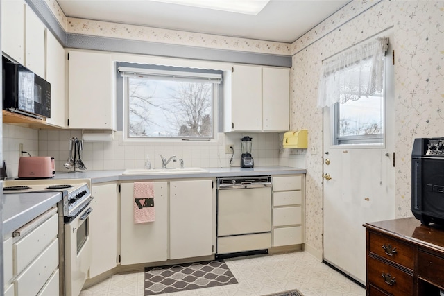 kitchen with sink, white appliances, white cabinets, and backsplash