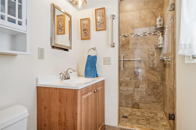 bathroom with vanity, a tile shower, and toilet