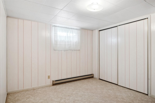 carpeted spare room featuring a baseboard heating unit