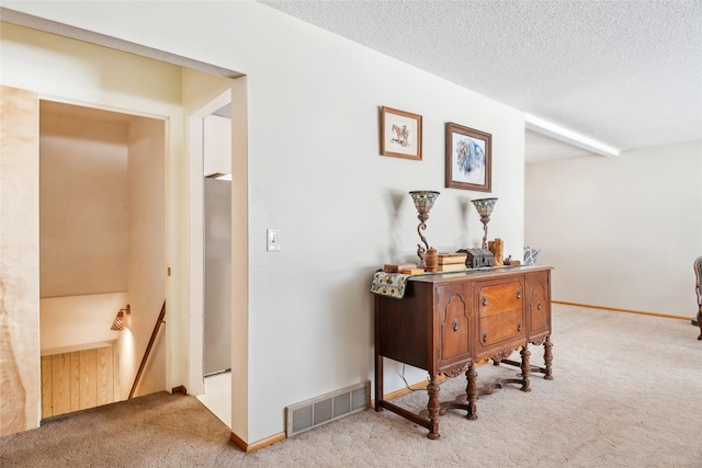 hallway with light colored carpet and a textured ceiling