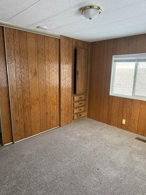 1730 N Hannaford St, Helena, MT 59601 - unfurnished room with visible vents, carpet flooring, and wood walls