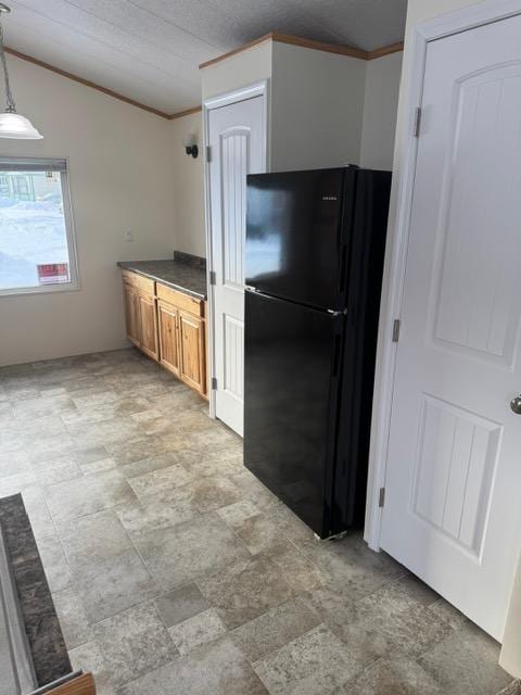 1730 N Hannaford St, Helena, MT 59601 - kitchen featuring ornamental molding, dark countertops, freestanding refrigerator, brown cabinets, and stone finish flooring