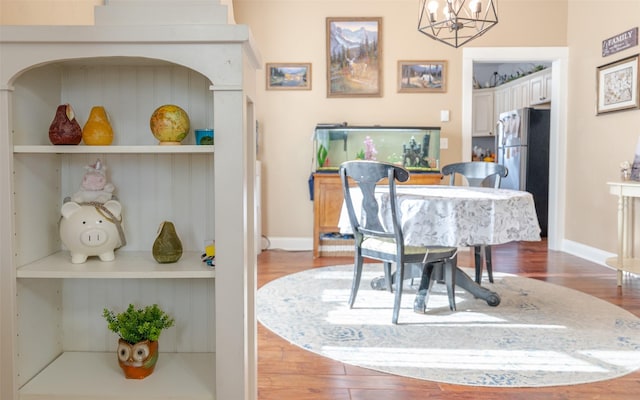 dining space featuring a notable chandelier, built in shelves, and wood-type flooring