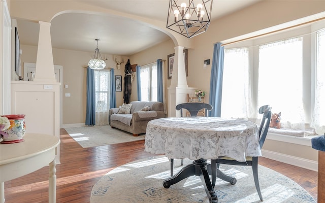 dining area with ornate columns and wood-type flooring