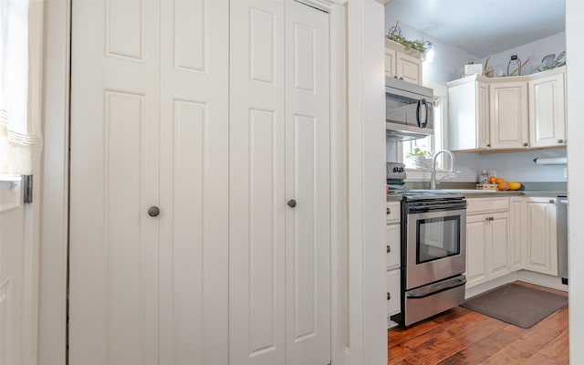 kitchen with stainless steel appliances, dark hardwood / wood-style flooring, and white cabinets