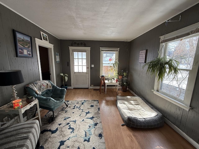 living room featuring hardwood / wood-style flooring, a textured ceiling, and wood walls