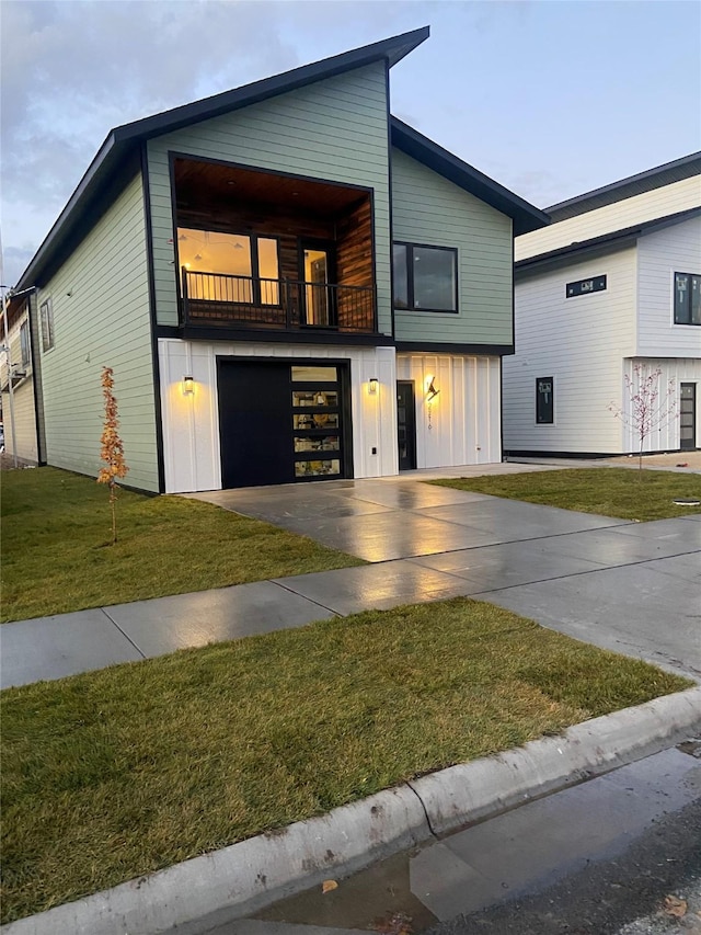 contemporary home featuring driveway, a garage, a balcony, board and batten siding, and a front yard