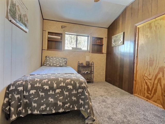 bedroom featuring lofted ceiling, wooden walls, and carpet