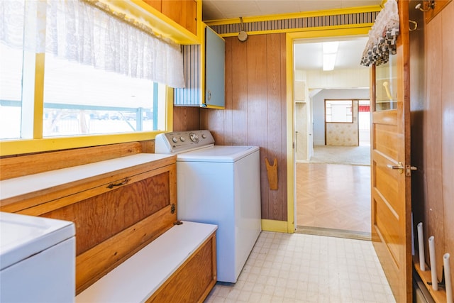 laundry room featuring independent washer and dryer, cabinets, plenty of natural light, and wood walls