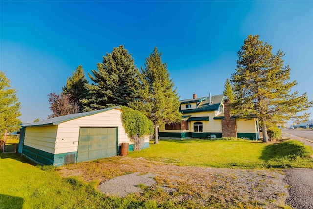 view of front of house with a garage, an outbuilding, and a front lawn