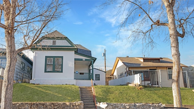 view of front of property with covered porch, a front yard, and fence