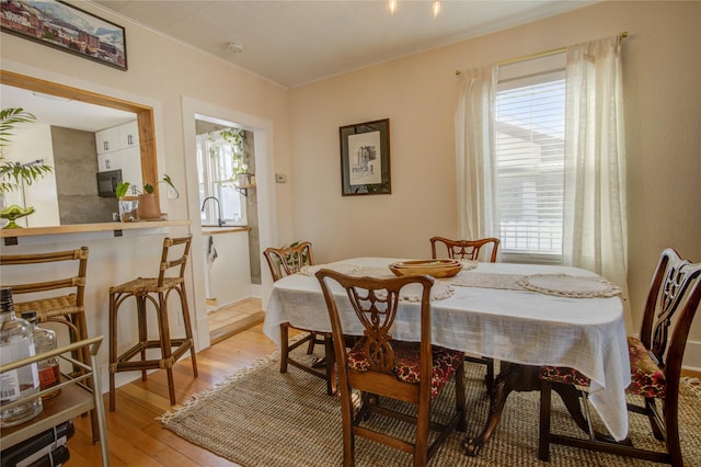dining space featuring light wood-type flooring, plenty of natural light, and crown molding