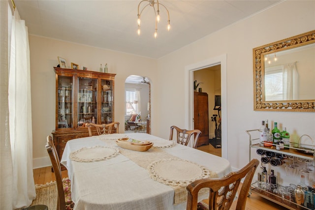 dining room with plenty of natural light, arched walkways, and light wood-style floors