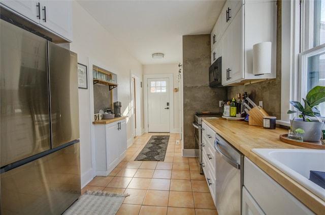 kitchen featuring white cabinets, appliances with stainless steel finishes, wooden counters, and light tile patterned flooring