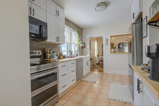 kitchen with light tile patterned floors, white cabinetry, and appliances with stainless steel finishes