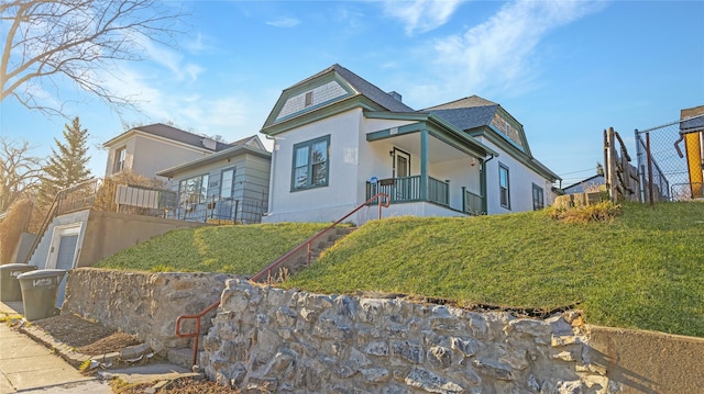 exterior space with stucco siding, stairs, and a shingled roof