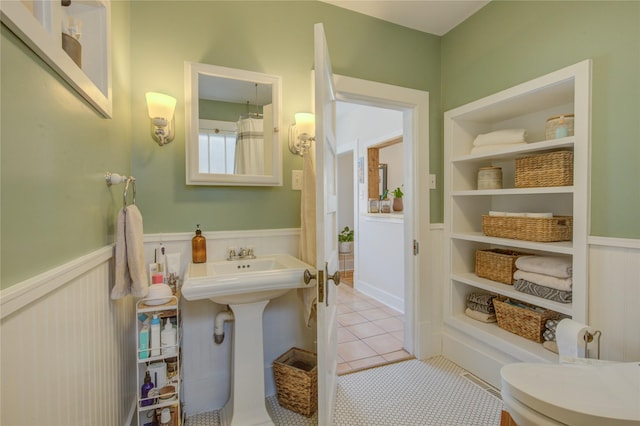 full bath with tile patterned floors, a wainscoted wall, and a sink